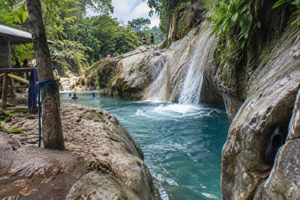 Turquoise waterfall pool surrounded by rock walls in a tropical forest canyon