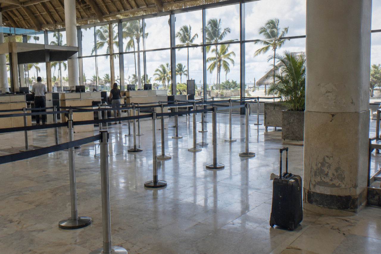 Airline check-in counters at a tropical airport terminal with palm trees visible through the glass