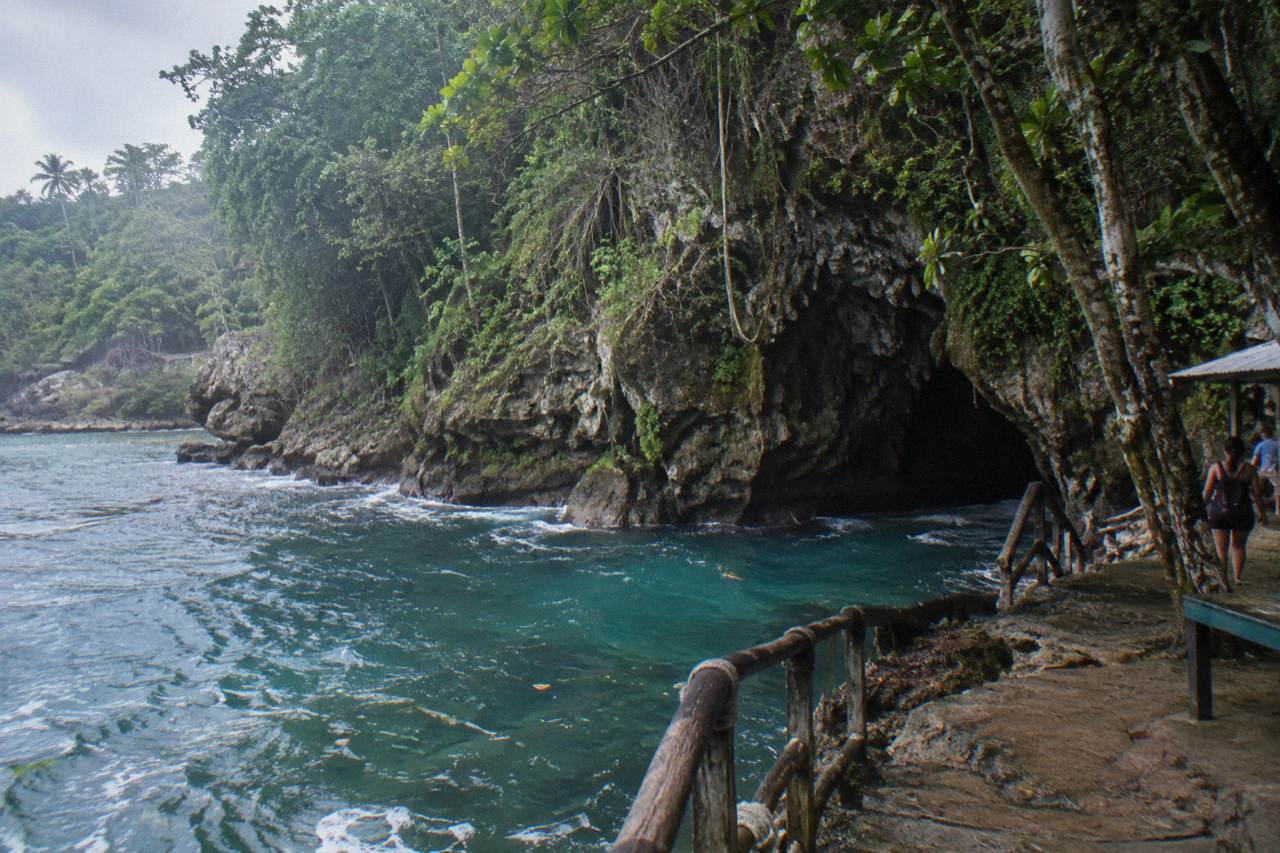 Limestone cave entrance surrounded by dense tropical forest in the Dominican Republic