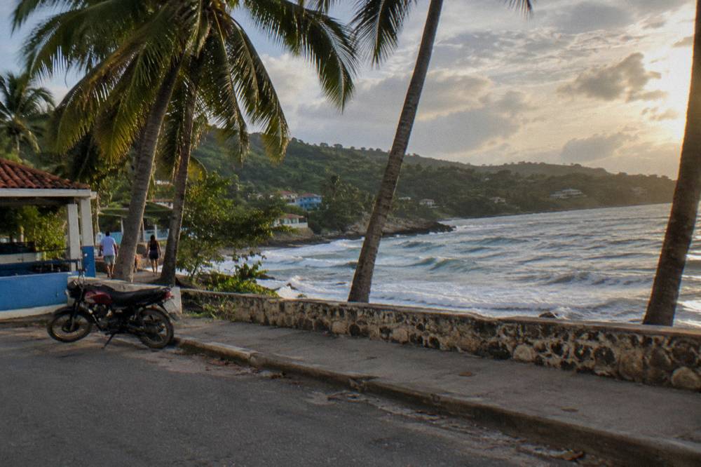 Coastal road with palm trees and green hills above Sosua