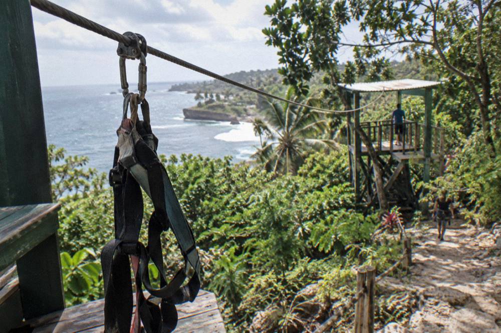 A zip line cable running through green jungle canopy toward a wooden platform