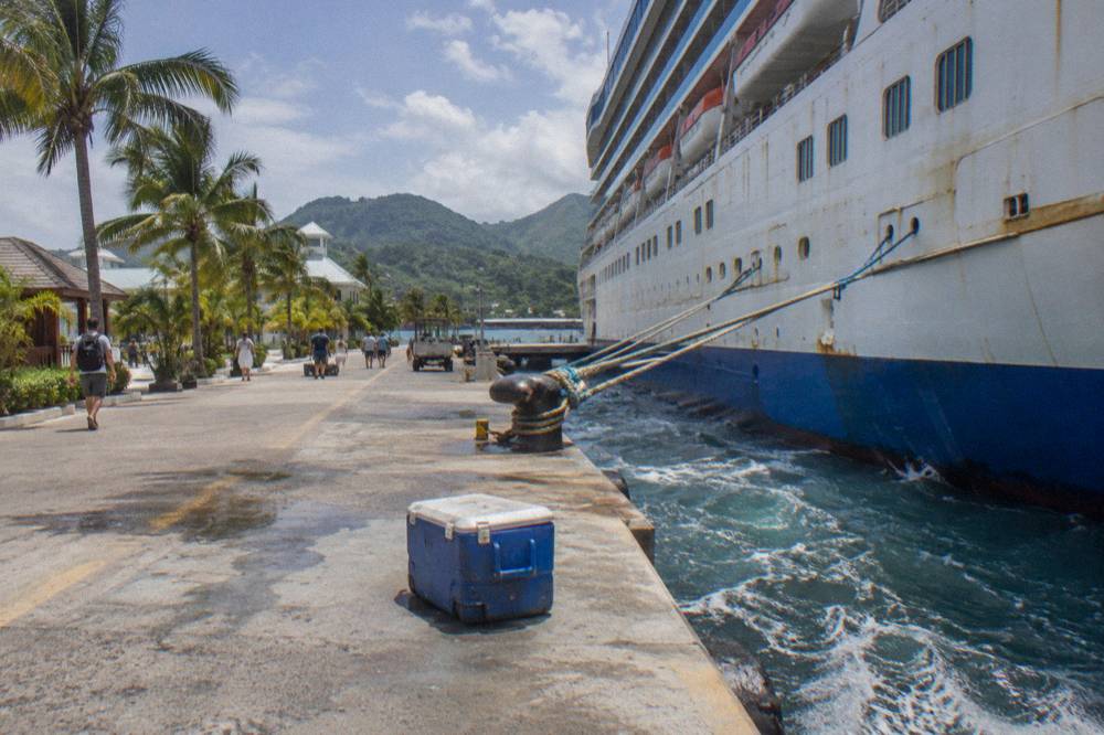 Cruise ship in a turquoise bay with green hills in the background
