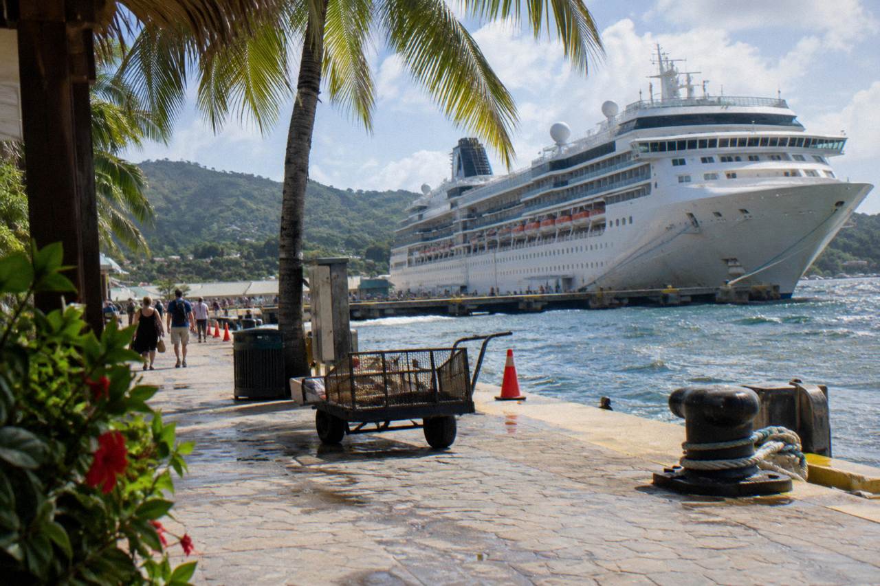 Cruise port pier with turquoise water, palm trees and distant visitors under a bright Caribbean sky