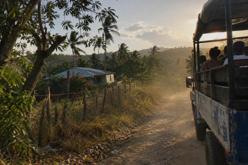 Open-air safari truck on a dirt road through green Dominican hills
