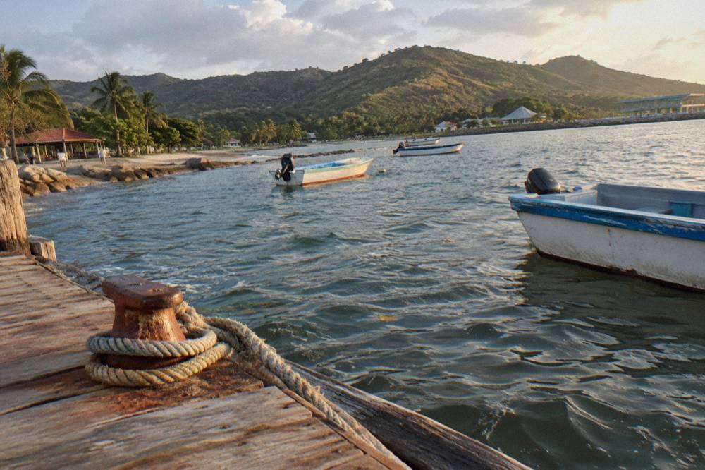 Wooden dock with small boats and green hills across a bay