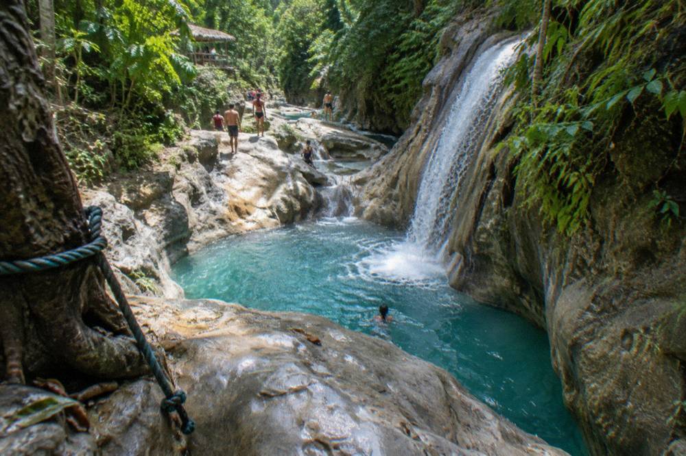 Tiered waterfall cascading into clear pools surrounded by wet rock
